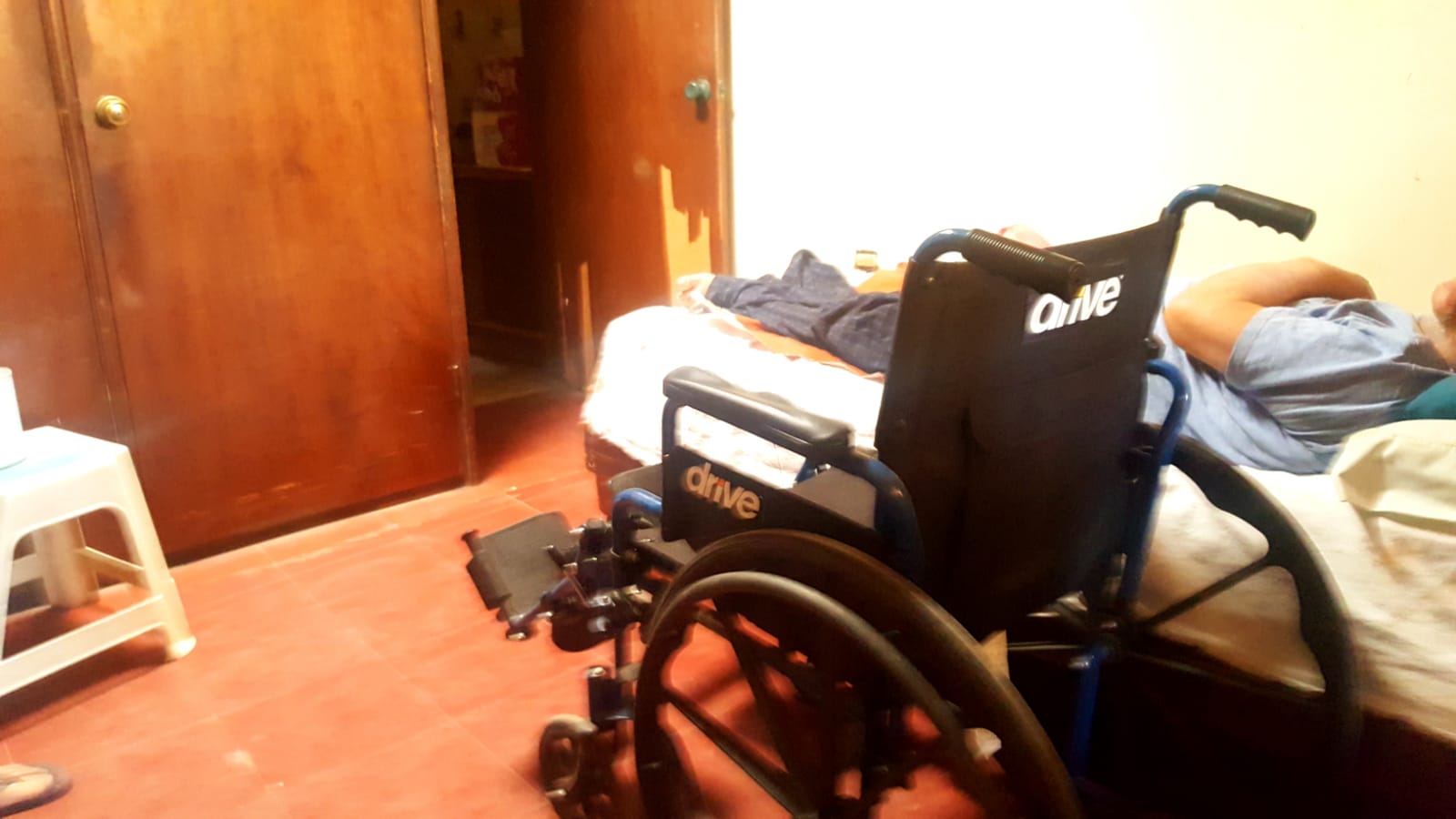Juan Manuel acostado con la silla de ruedas al costado de la cama